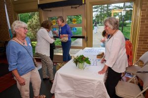 A member approaches another member who is manning a table